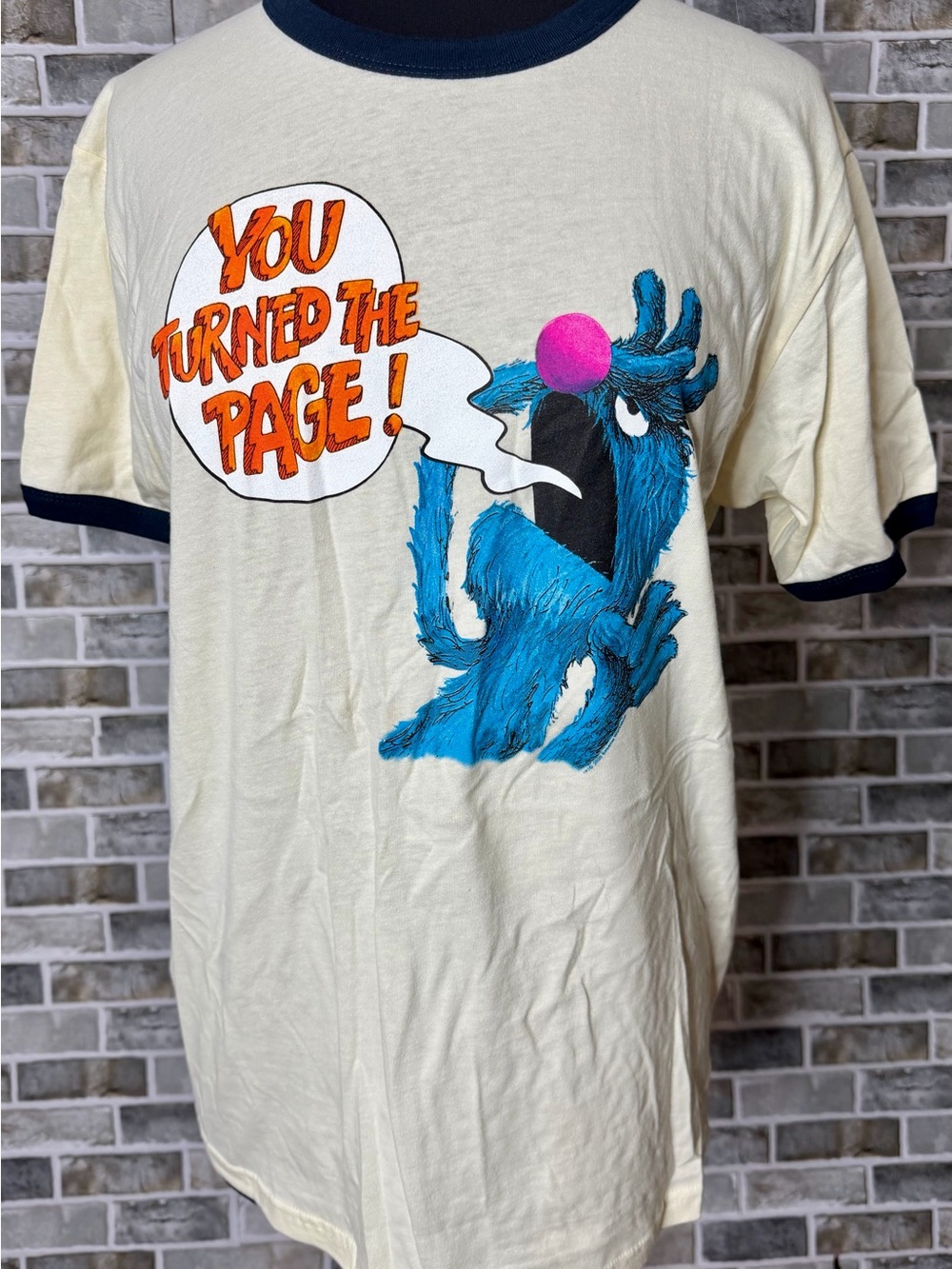Out of Print Cream Ringer Tee with Blue Monster and Orange Print